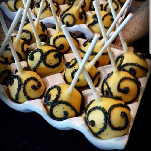 Yellow cake pops with black decoration.