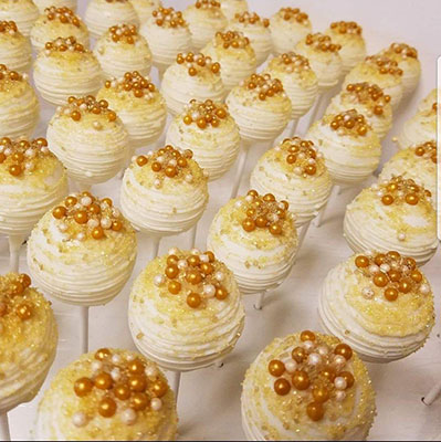 Cream cake pops with golden decorations.